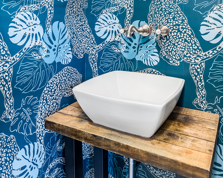 bold, interesting wall paper surrounding basin sink with wall mounted faucet