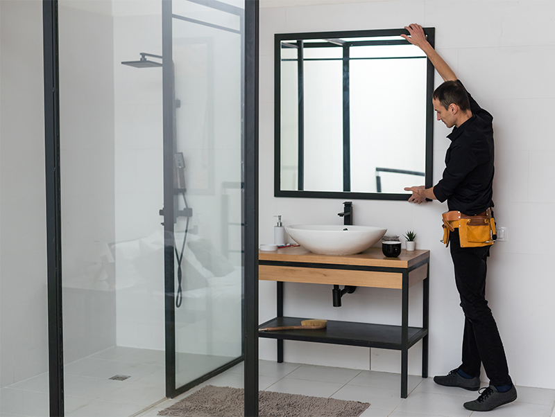 The-worker-installs-the-mirror-in-the-bathroom